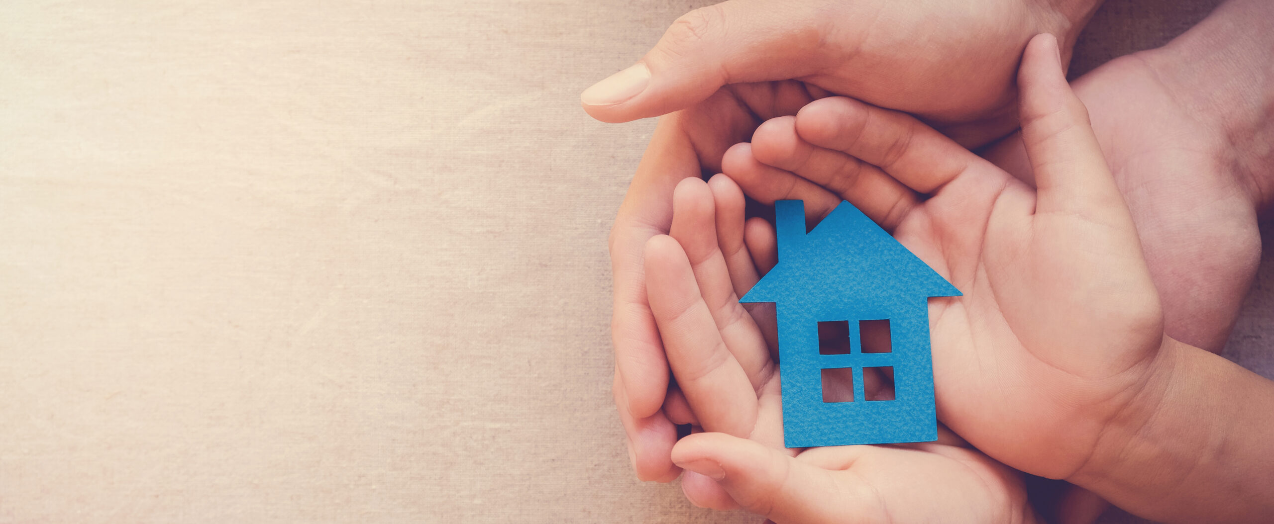 Hands holding a blue model house